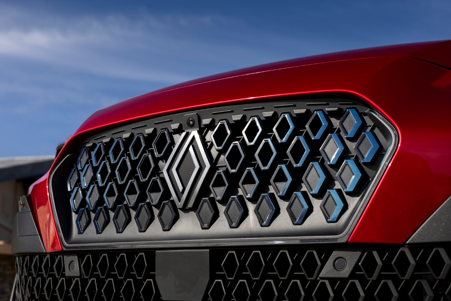 Gros plan de la calandre avant d&rsquo;une Renault Clio 6 rouge avec logo Renault et motifs graphiques modernes